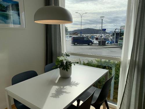 a white table with chairs and a window with a view of a harbor at Modern apartment in the Harbour of Jørpeland in Jørpeland