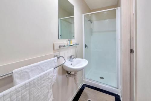 a white bathroom with a sink and a shower at Oasis Studio in City Central - Aircon and FREE WIFI in Auckland