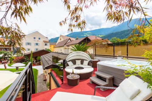 a balcony with a hot tub and chairs on a roof at Hotel Traube in Bressanone