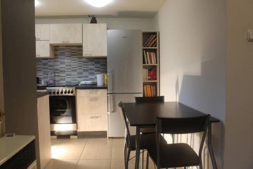 een keuken met witte kasten en een zwarte tafel en stoelen bij Green garden apartment in Szeged