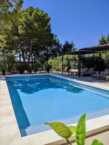 une grande piscine bleue avec des arbres en arrière-plan dans l'établissement Cottage Aixois Mas de la Granette, à Aix-en-Provence
