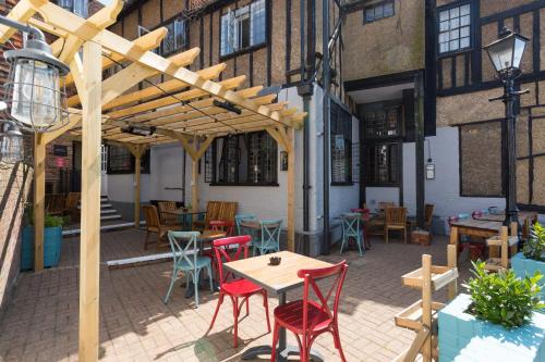 a patio with tables and chairs and a wooden pergola at The George Hotel & Brasserie, Cranbrook in Cranbrook