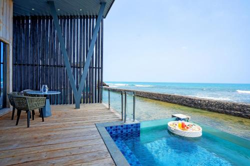 a swimming pool on a deck with the ocean at Aston Anyer Beach Hotel in Anyer