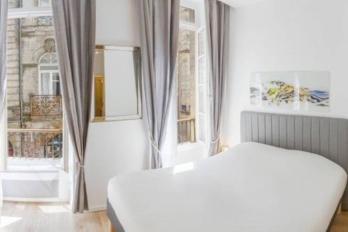 a bedroom with a bed and two windows at Logement de charme - Saint Pierre - Cœur historique Bordeaux in Bordeaux