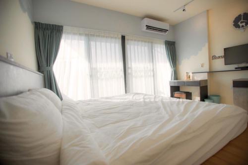 a white bed in a bedroom with a window at A Day in Lukang Homestay in Lugang
