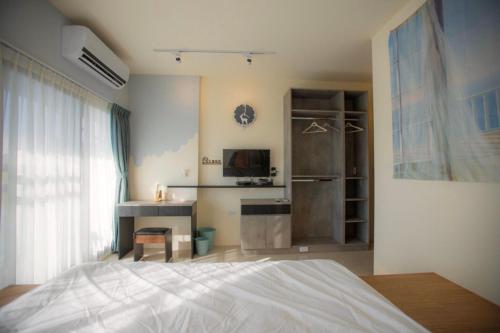a bedroom with a bed and a desk and a television at A Day in Lukang Homestay in Lugang