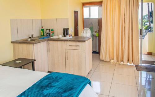 a kitchen with a bed and a sink in a room at 15 @ Porter Guesthouse in Port Shepstone