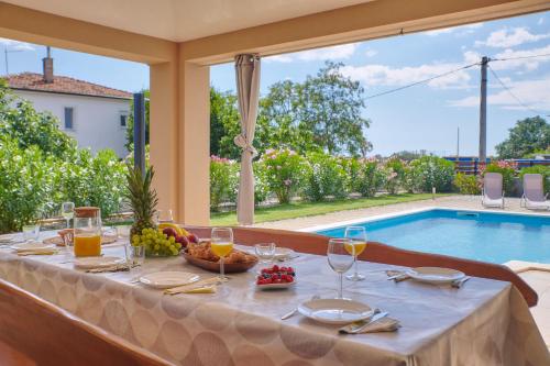 a table with wine glasses and a bowl of fruit next to a pool at Villa Bartona for 8 persons with private Swimmingpool in Pula
