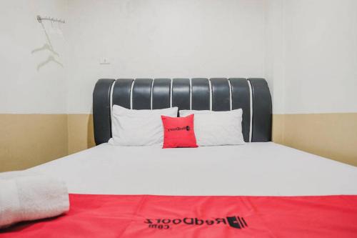 a bed with two pillows and a red blanket at RedDoorz @ Jalan STM Medan in Medan