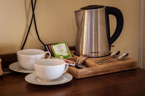 a coffee pot and two cups on a table at Hotel Rycerski in Czeladź