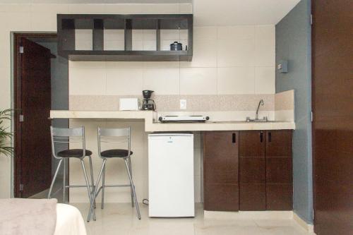 cocina con 2 taburetes y refrigerador blanca en CondoHotel 5th Avenue Basic Studio, en Playa del Carmen