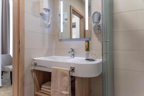 ein Bad mit einem Waschbecken und einem Spiegel in der Unterkunft Grand Hotel Rogaska in Rogaška Slatina