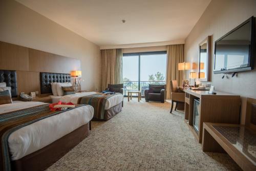 a hotel room with two beds and a desk at Korineum Golf & Beach Resort in Kérynia