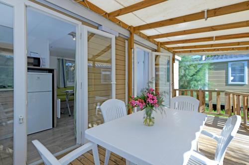 a white table and chairs on a deck with a kitchen at Club del Sole Vigna sul Mar Family Collection in Lido di Pomposa