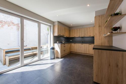 una cocina con armarios de madera y una gran ventana en Maison Jean, en Nieuwpoort