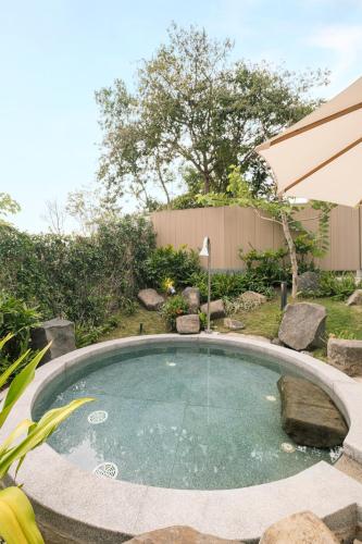 a small swimming pool in a yard with an umbrella at Minera Hot Springs Binh Chau in Binh Chau