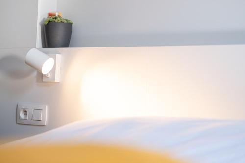 a room with a bed with a light switch and a plant at PANACHE - BIKE EN SLEEP HOTEL in La Roche-en-Ardenne