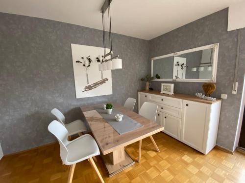 comedor con mesa de madera y sillas blancas en Ferienwohnung Baumberger-Auszeit, en Coesfeld