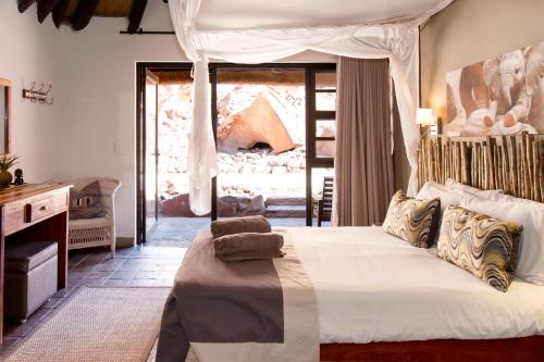 a bedroom with a bed and a large window at Twyfelfontein Country Lodge in Twyfelfontein