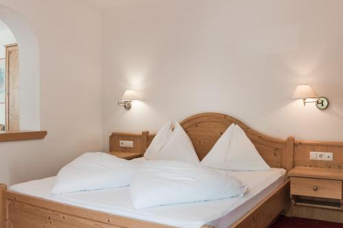 a bedroom with a bed with white sheets and pillows at Park Hotel Villa Etschland in Plaus