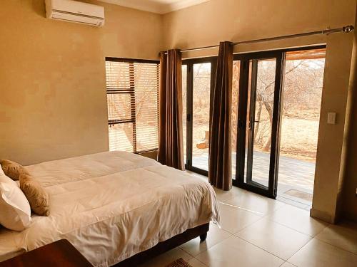 een slaapkamer met een bed en een groot raam bij Elements Private Golf Reserve in Bela-Bela