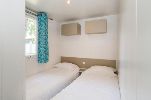 two beds in a small room with a window at Club del Sole Vigna sul Mar Family Collection in Lido di Pomposa