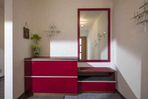 a hallway with a red dresser and a mirror at Appartements Linda in Ellmau