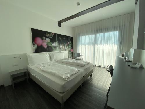 a bedroom with a large white bed and a window at Hotel Riviera in Riva del Garda