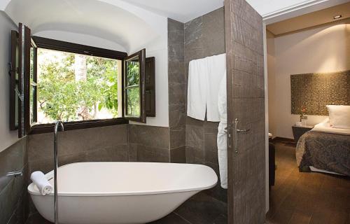 a bathroom with a bath tub and a bedroom at Hospes Palacio del Bailio, a Member of Design Hotels in Córdoba
