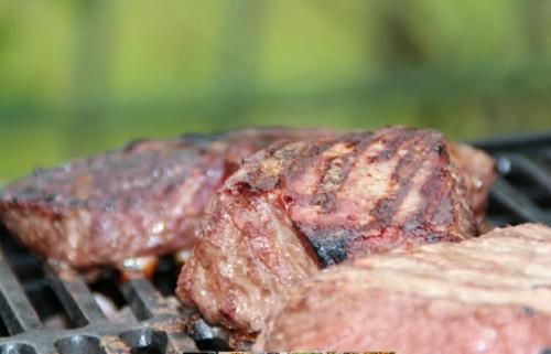 due pezzi di carne che cuociono su una griglia di Agriturismo Green Valley a Cene