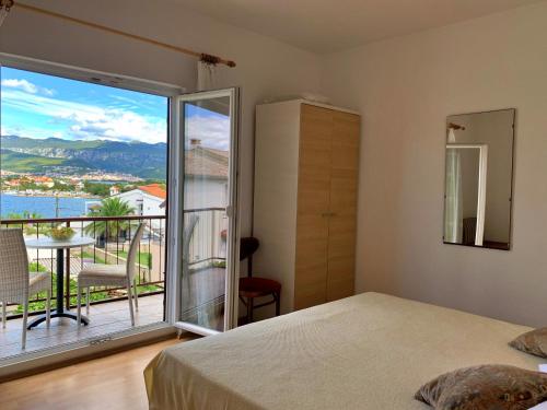 a bedroom with a bed and a large window with a view at Apartments Nevenka P. in Šilo