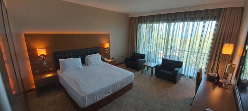 a hotel room with a bed and a desk and chairs at Korineum Golf & Beach Resort in Kérynia
