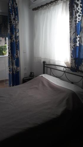 a bedroom with a bed and a window with curtains at Nina Rooms (apartments) in Artemida