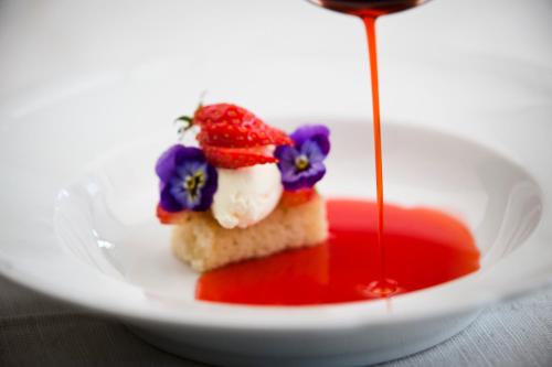 a white plate with a piece of cake with red sauce at Ulvsby Herrgård in Sunne