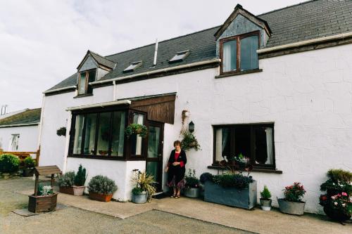 a woman standing in the doorway of a white house at The Farmhouse Lochmeyler in Llandeloy