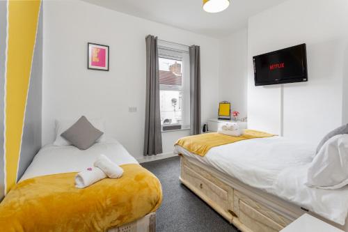 a bedroom with two beds and a flat screen tv at Comfortable Liverpool Townhouse - FREE parking in Liverpool