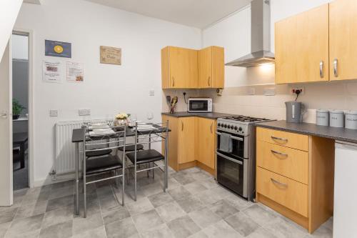 a kitchen with a stove and a table with chairs at Comfortable Liverpool Townhouse - FREE parking in Liverpool