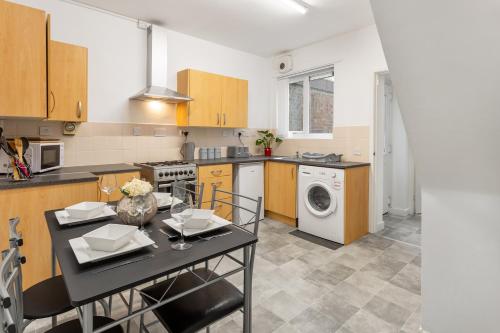 cocina con mesa de comedor, lavadora y secadora en Comfortable Liverpool Townhouse - FREE parking, en Liverpool