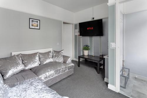 a living room with a couch and a flat screen tv at Comfortable Liverpool Townhouse - FREE parking in Liverpool