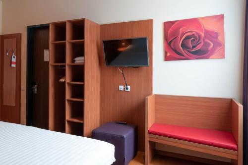 a room with a bed, chair, desk and a television at Star G Hotel München Schwabing in Munich