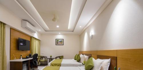 a hotel room with two beds and a desk at Hotel Kheni in Chennai