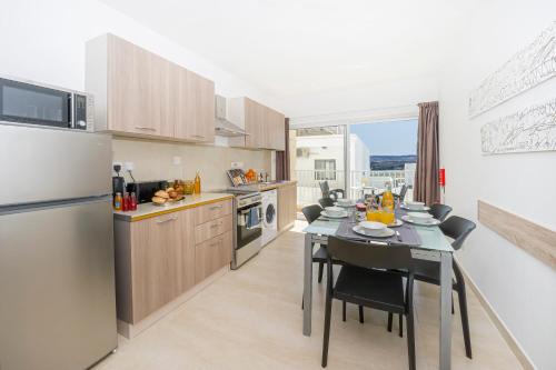a kitchen with a dining table and a refrigerator at Summer Breeze Comfort Sunny Apartments close to the sandy beaches - by Getawaysmalta in Mellieħa