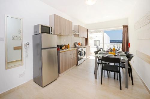 a kitchen with a dining table and a refrigerator at Summer Breeze Comfort Sunny Apartments close to the sandy beaches - by Getawaysmalta in Mellieħa