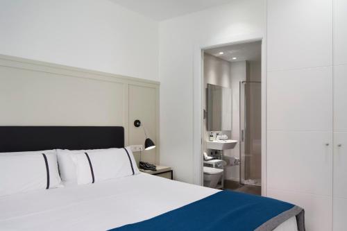 a bedroom with a large white bed and a bathroom at Hotel SANSEbay in Donostia-San Sebastián