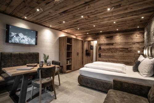 ein Hotelzimmer mit einem Bett, einem Tisch und einem TV in der Unterkunft Apartment Alpinflair 1 in Kaprun