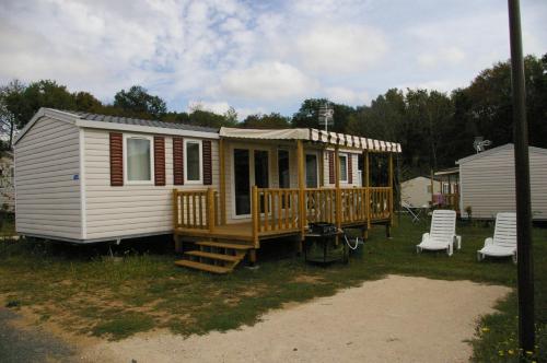 a small white house with a porch and chairs at MHVACANCES LOUENT PLUSIEURS MOBILHOMES DANS CAMPING 4 ETOILES PROCHE CHATEAUX et ZOO BEAUVAL in Onzain
