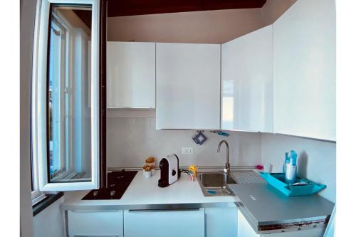 una cucina con armadi bianchi, lavandino e finestra di Dependance Castiglione with pool and view a Ischia
