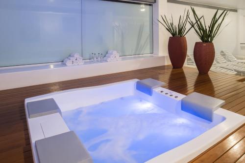 uma banheira de hidromassagem numa sala de estar com dois vasos em Serrazul Hotel Distributed By Intercity em Gramado