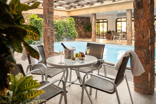 um pátio com uma mesa e cadeiras ao lado de uma piscina em Serrazul Hotel Distributed By Intercity em Gramado