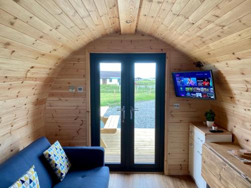 a living room with a blue couch in a wooden house at Fuaim na Mara - Self Catering Pod in Creagorry